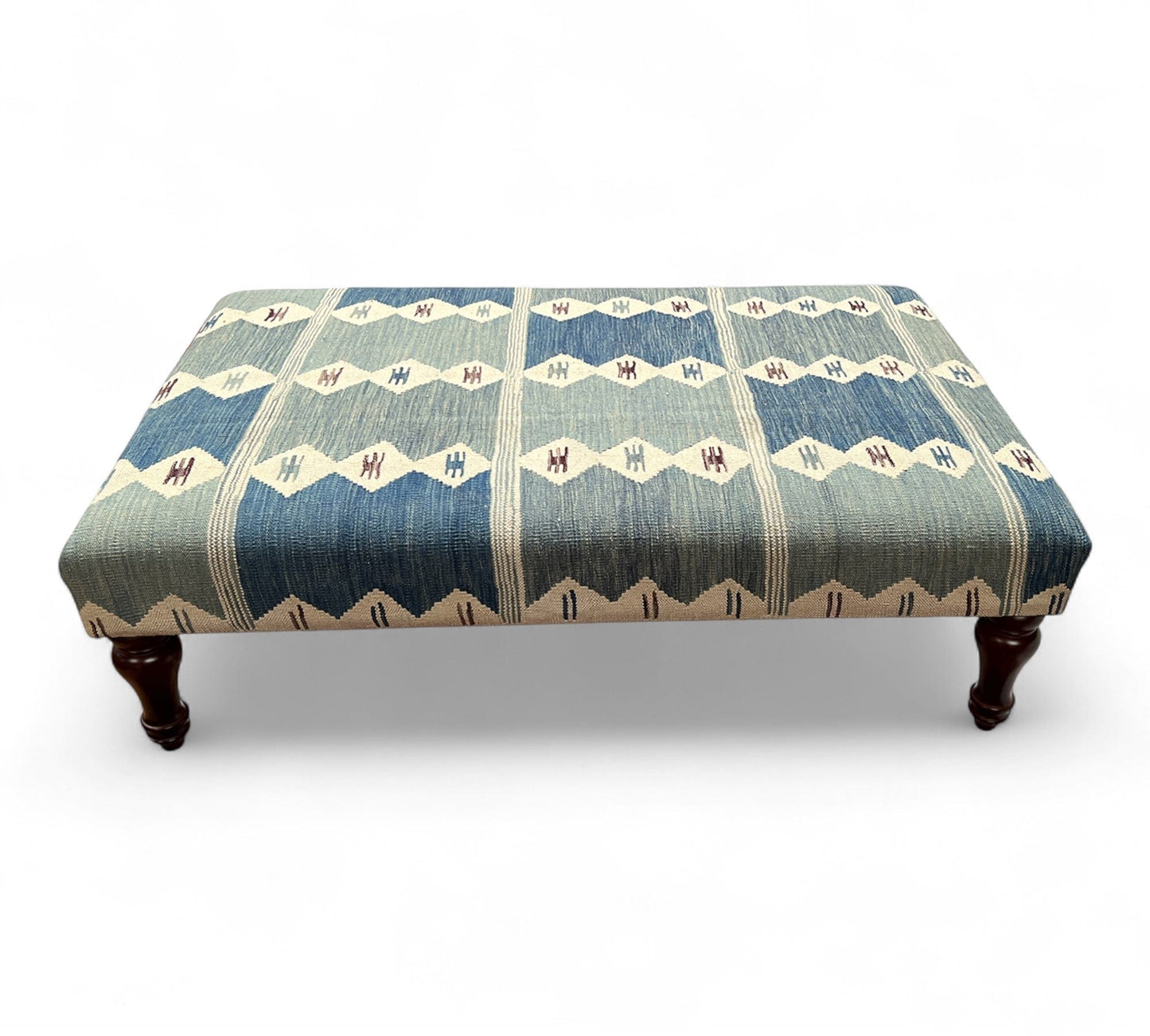 Patterned kilim ottoman with wooden legs on a white background